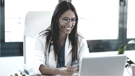 Doctora utilizando un computador y sonriendo
