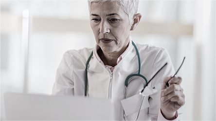 Doctora mirando un computador con unas gafas en la mano